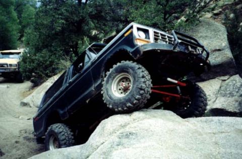 2002 Ford F-350 - A black Ford Bronco navigates a rocky off-road trail, with another vehicle visible on the left.