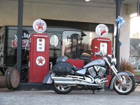 2006 Victory Kingpin - A silver motorcycle is parked next to vintage Texaco gas pumps, with an old truck visible behind them.