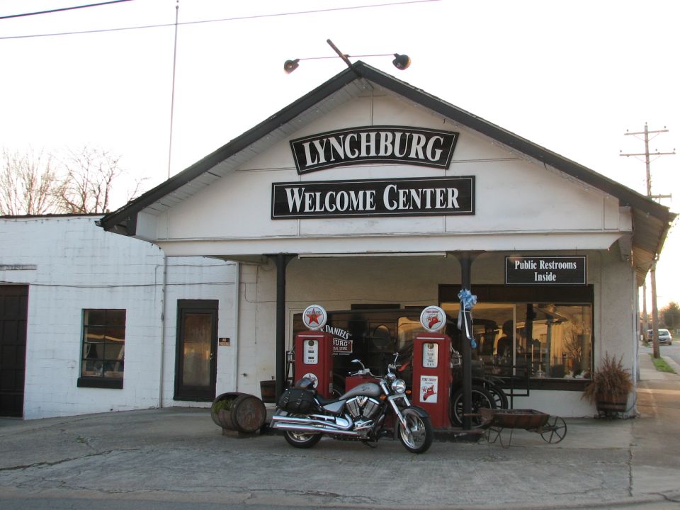 Motorcycle parked in front of Lynchburg Welcome Center with vintage gas pumps