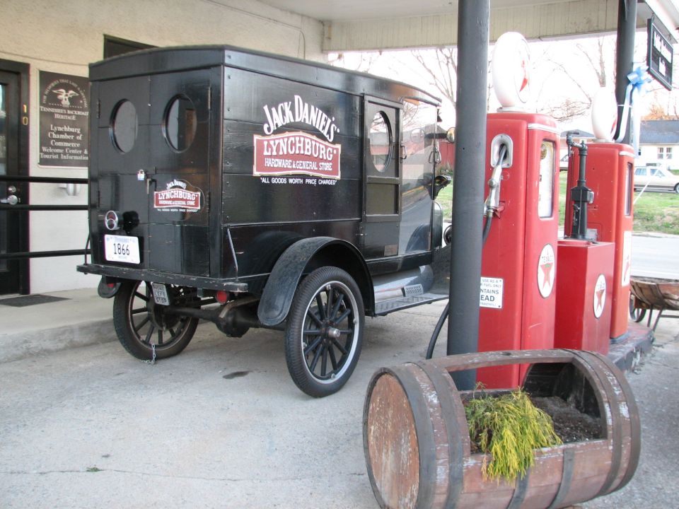 Black delivery truck with Jack Daniel's Lynchburg signage parked next to red gas pumps