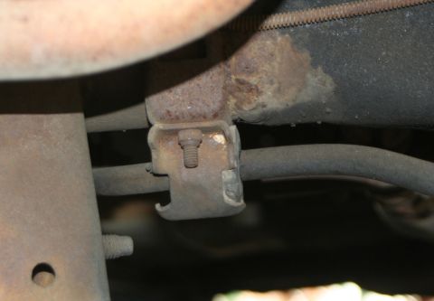 1976 Ford Ranchero - Underside view of a rusted suspension bracket and bar, likely from an older vehicle.