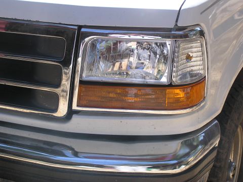1993 Ford Bronco - The front end of a white Ford F-Series truck is shown, chrome accents around the headlights and grille.