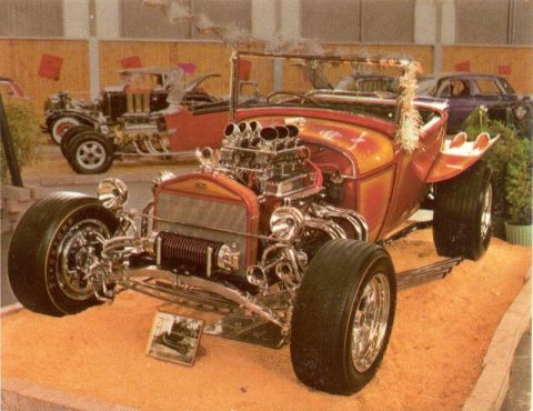 1969 Lincoln Continental - A heavily modified hot rod with a prominent V8 engine is displayed, with other vehicles in the background.