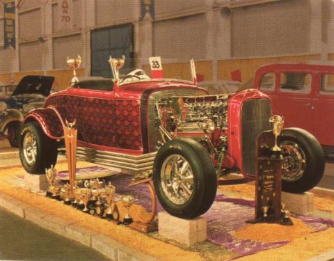 1969 Lincoln Continental - A highly customized hot rod is displayed indoors, adorned with numerous trophies, suggesting it's a show car.
