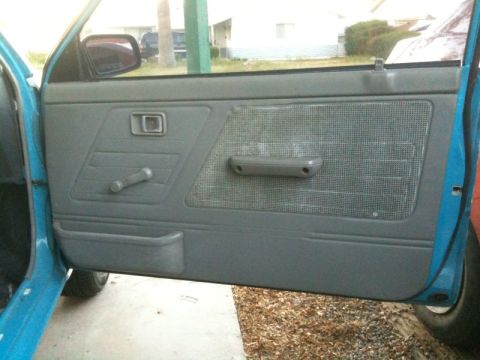 1991 Ford Festiva - Close-up of a car's interior door panel with a window crank and storage pocket.