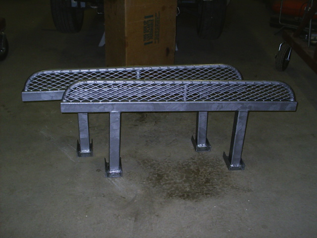 Fabricated steel rock sliders with mesh tops and mounting legs on garage floor