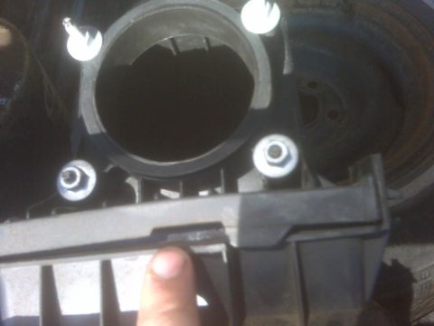 1994 Ford F-150 - A close-up view of an engine intake part, showing bolts and a finger indicating a connection point.