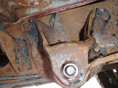 1995 Ford Bronco - Close-up view of heavily rusted frame components, including a bracket and bolt.