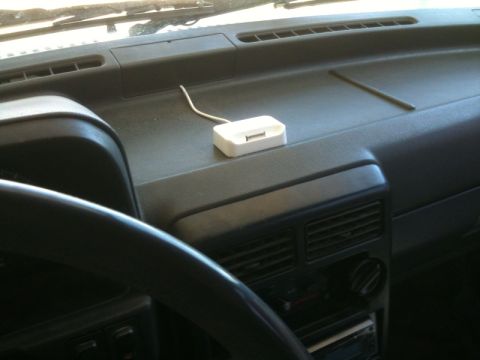 1991 Ford Festiva - The dashboard of a vehicle shows a white charging dock connected to a power source.