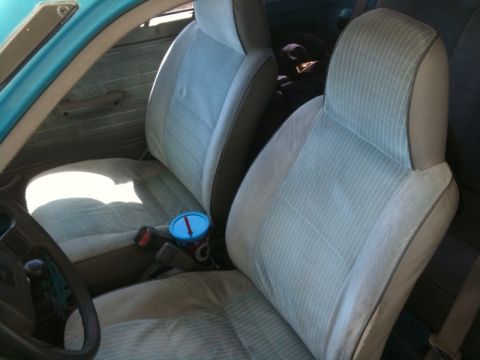 1991 Ford Festiva - Interior view of a car with striped fabric seats and a blue cup holder.