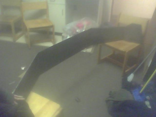 Black curved object, possibly a car part, lying on the floor