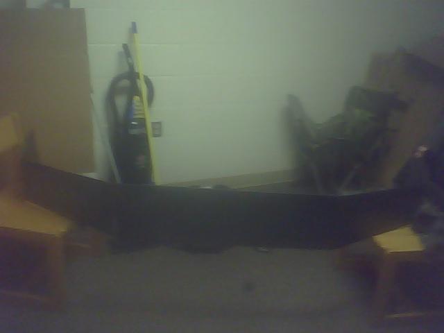 Black car bumper, possibly from a truck, lying on the floor indoors