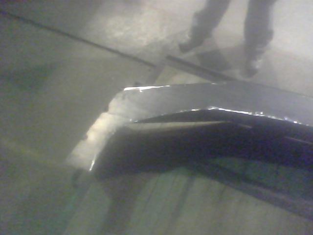 Truck bed with damaged metal trim and reflection of people's legs