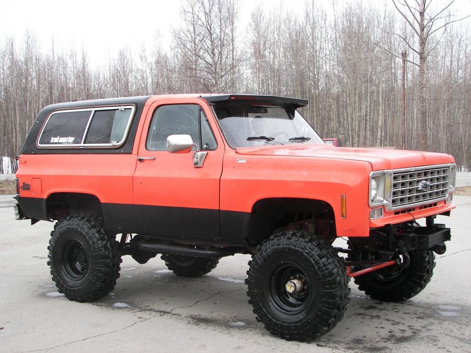 Orange and black lifted SUV with large tires, 1973 grille
