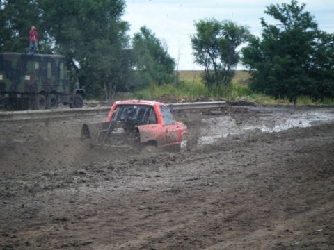 2000 Dodge 1500 - A modified pickup truck navigates a challenging mud bog, with a large camouflaged truck observing from the side.