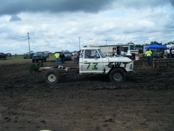 White pickup truck chassis with cab, number 73 on door, in mud. Older model
