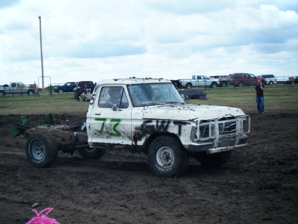 White pickup truck with green 73 and WT painted on side, mud-covered