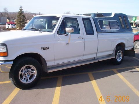 1995 Ford F-250 - A white Ford F-250 pickup truck with a blue camper shell is parked in a lot.
