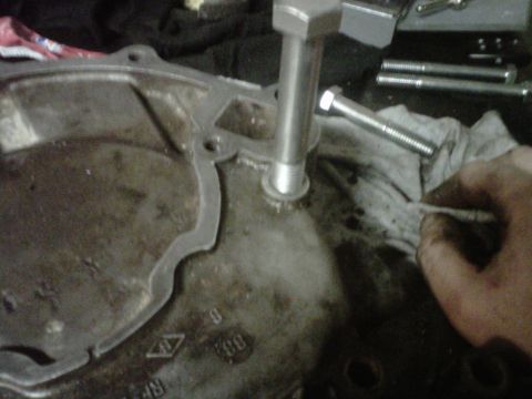 1995 Ford Bronco - A close-up view of an engine part with bolts being worked on, possibly during a repair or maintenance procedure.