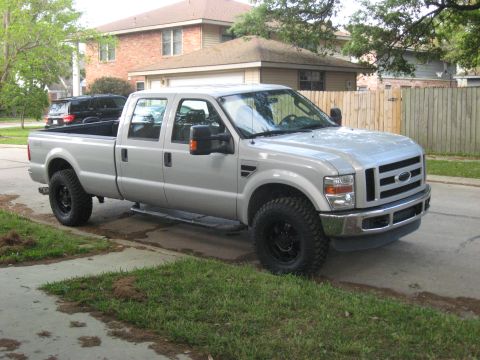 2008 Ford F-250 - A silver crew cab pickup truck is parked on the side of a residential street.