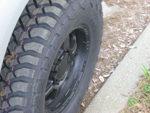 2008 Ford F-250 - Close-up of a black off-road tire and wheel on a white vehicle.