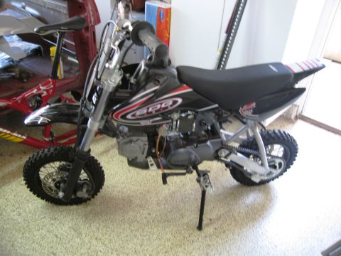 1986 Ford Bronco - A dirt bike with "SDG" graphics is shown from the side, parked indoors.