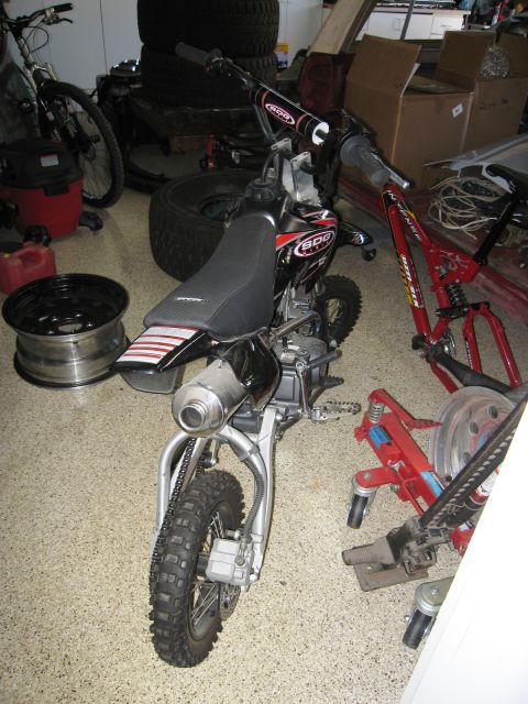 1986 Ford Bronco - A dirt bike is parked in a garage with other bicycles and tires around it.