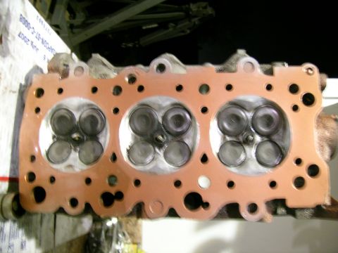 1995 Ford Probe - Engine cylinder head with gasket, valves visible. Part number visible on box in background.