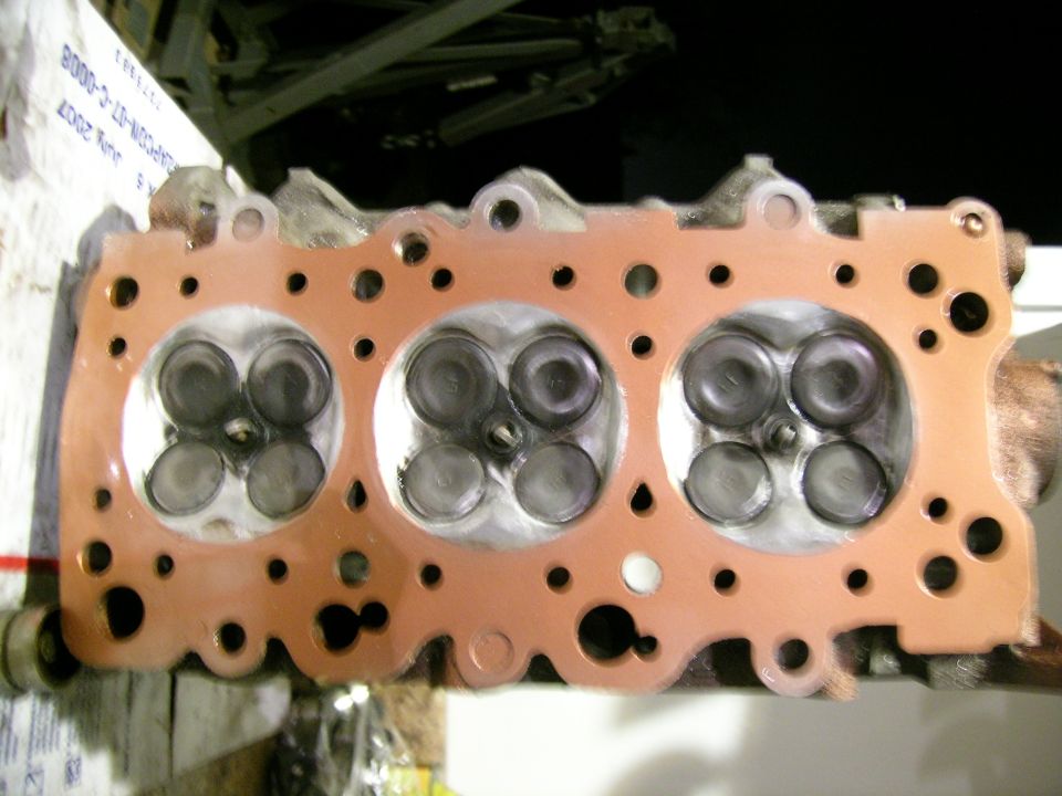 Engine cylinder head with copper gasket installed, showing valves