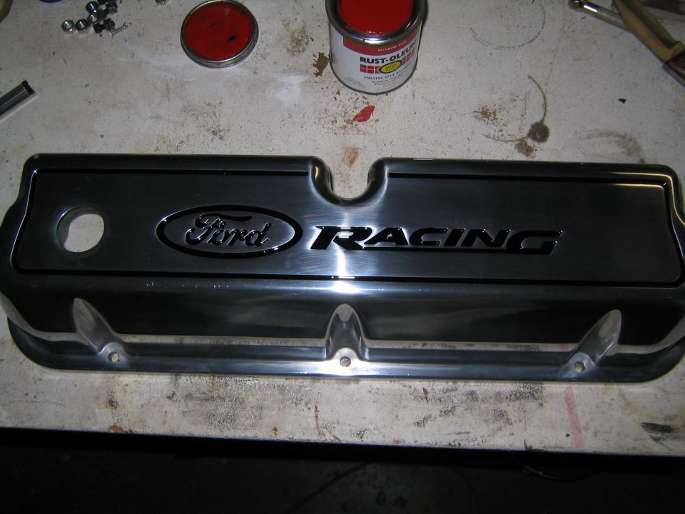 Chrome Ford Racing valve cover on a workbench with paint cans