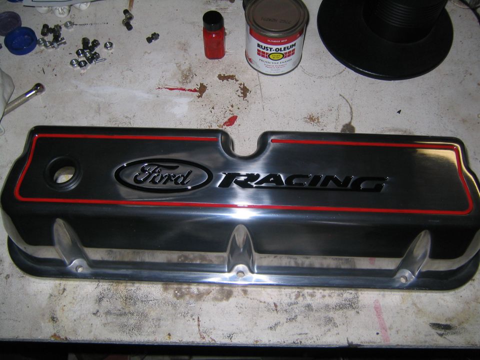 Black and red Ford Racing valve cover on a workbench