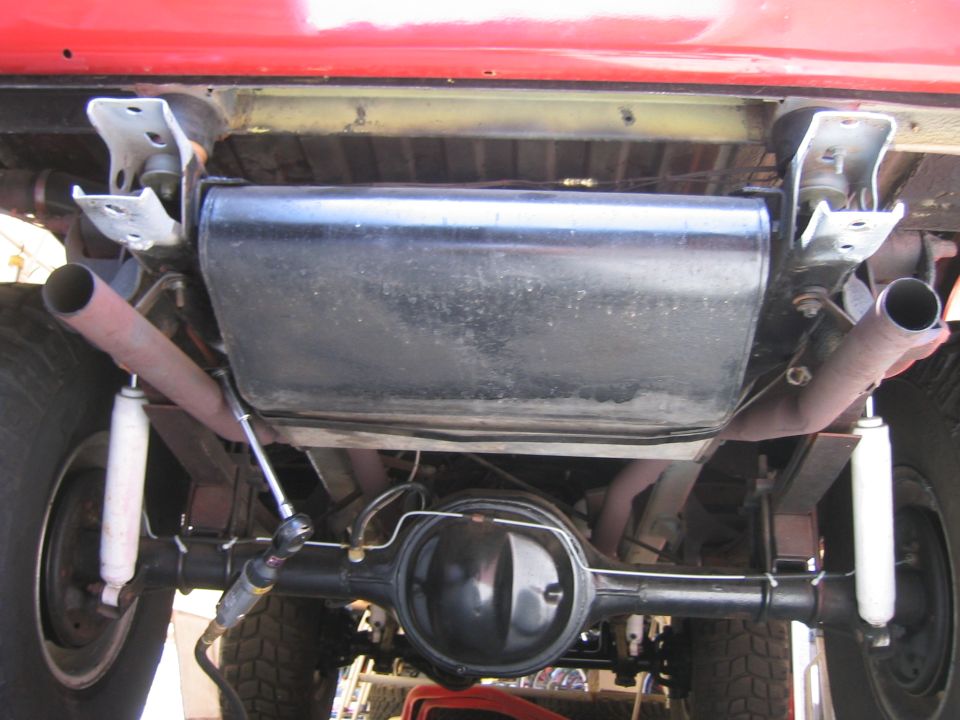 Underside view of a red truck showing muffler and rear axle