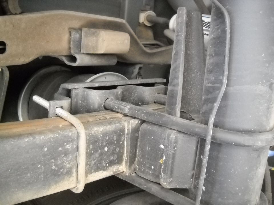 Close-up of a truck's rear suspension showing a rubber bump stop and U-bolt