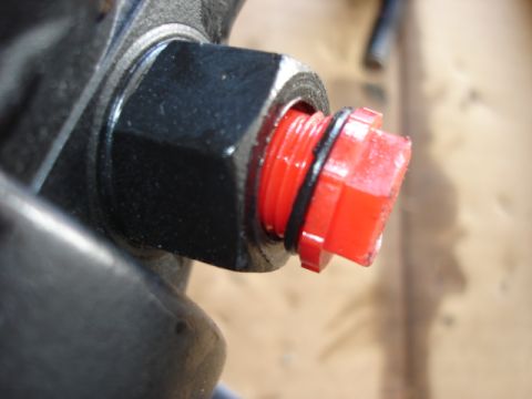 1992 Ford Bronco - A red plastic cap is threaded onto a bolt, with a black O-ring visible.