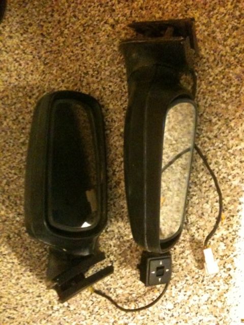 1991 Ford Festiva - Two automotive side mirrors are shown, one appearing to be a replacement part with wiring and a control switch.