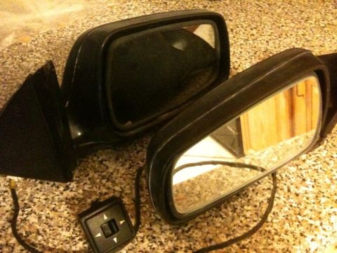 1991 Ford Festiva - Two black side mirrors and a power mirror control switch are displayed on a speckled surface.