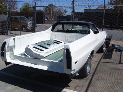 1973 Ford Ranchero - A white Ford Ranchero pickup truck sits in a lot, its bed empty except for a metal panel.