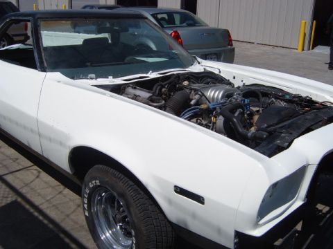 1973 Ford Ranchero - White 1973 Ford Ranchero shows its engine bay, with a black roof and another vehicle visible in the background.
