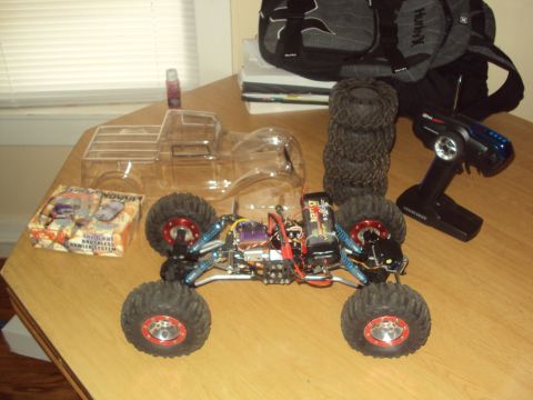 1992 Ford Ranger - RC rock crawler parts laid out on a table, including a clear body, tires, and remote control.