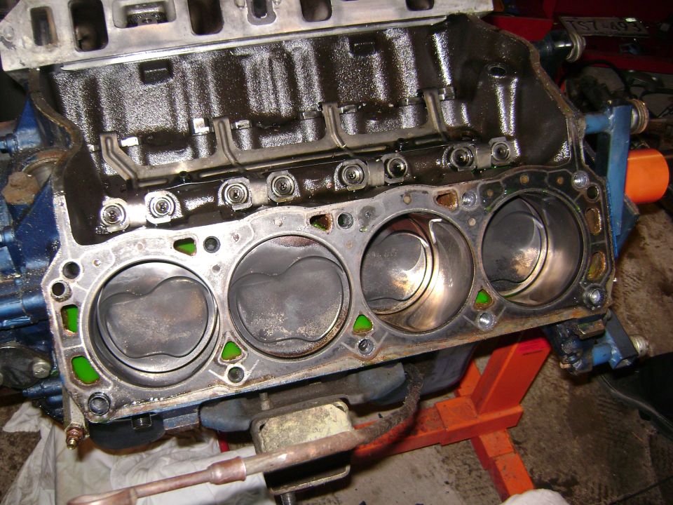 Engine block with pistons visible, showing cylinder walls and gasket