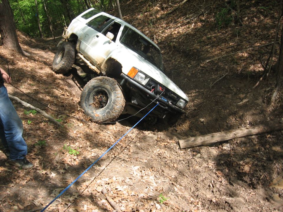 White 1980s Toyota 4Runner off-roading, winched up a steep, muddy incline