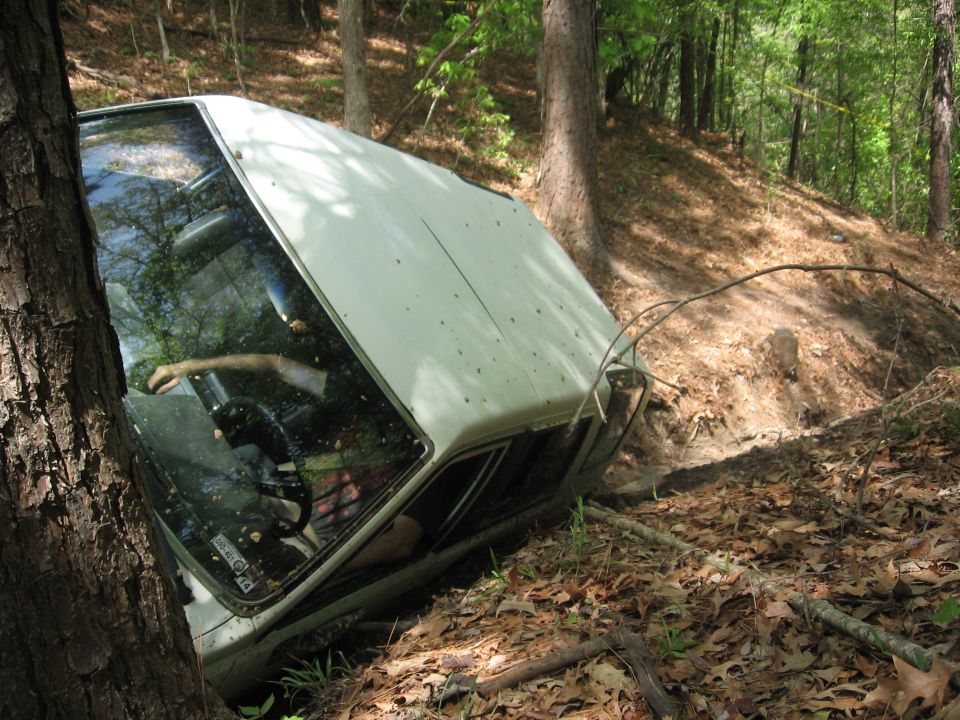 1984 Ford Bronco II stuck in a wooded ditch, driver's side visible