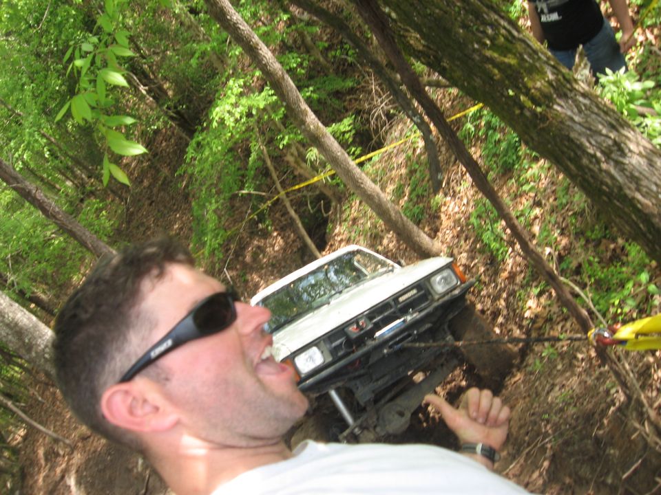 1984 Ford Bronco II winched up a wooded incline with a man in the foreground