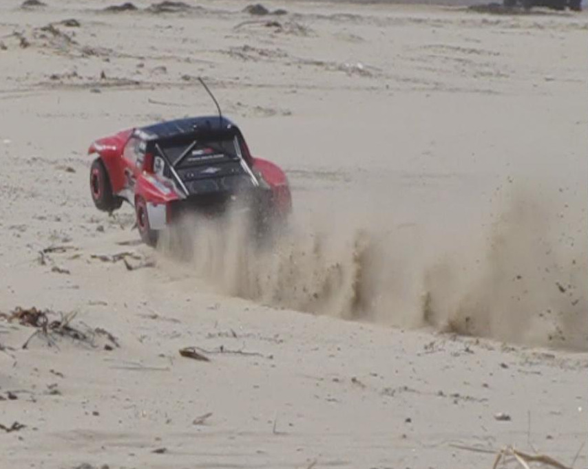 RC trophy truck kicking up sand on a beach