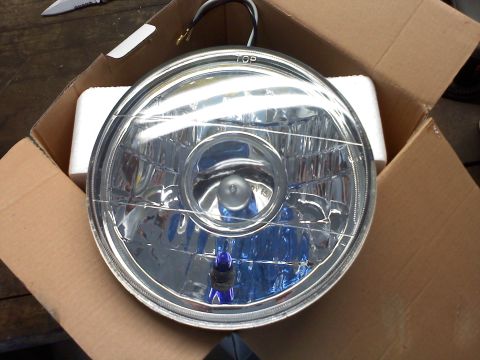 1992 Ford Bronco - A single headlight assembly is shown inside its packaging, ready for installation.