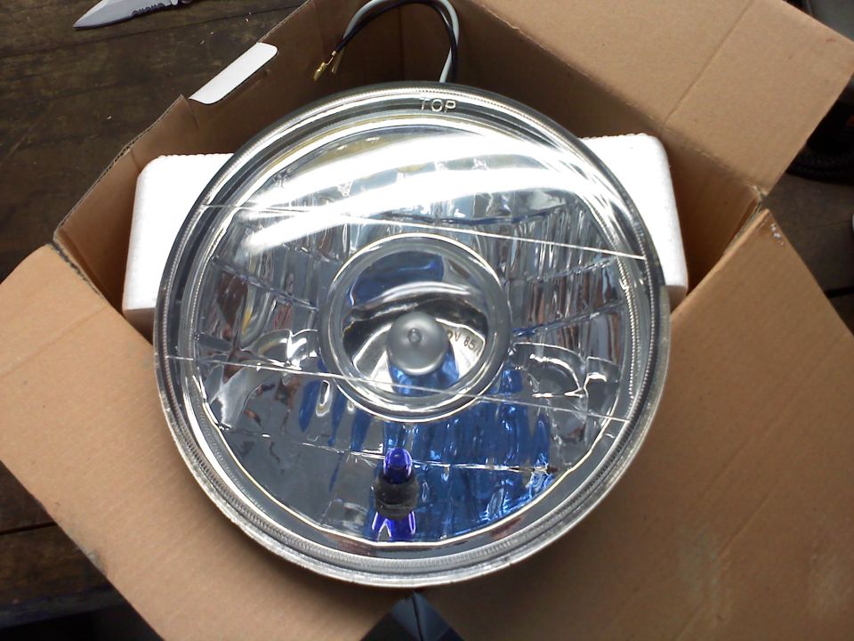 Headlight in cardboard box, chrome bezel, clear lens with blue bulb