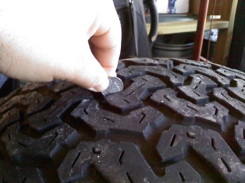 1992 Ford Bronco - Tire tread depth is being measured with a coin to check wear.