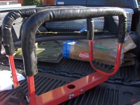 1980 Chevrolet Camaro - A red rack with black padding is loaded into the bed of a pickup truck with some boxes.