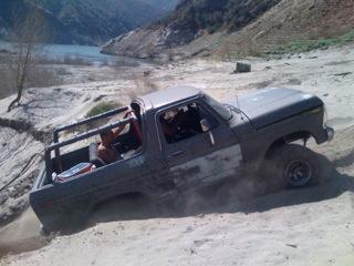 1978 Ford Bronco - This 1978 Ford Bronco is navigating a challenging off-road terrain with a body of water visible in the distance.