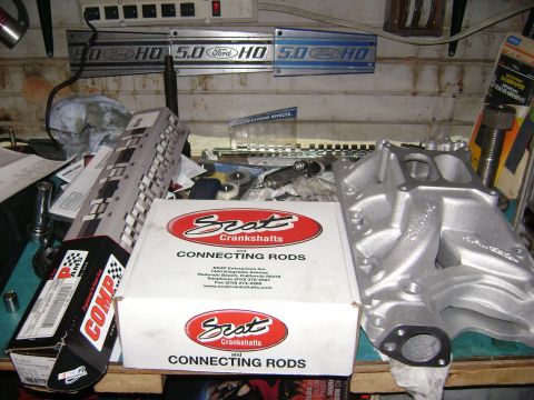 1981 Ford Mustang - Engine parts, including an intake manifold and connecting rods, are laid out on a workbench.